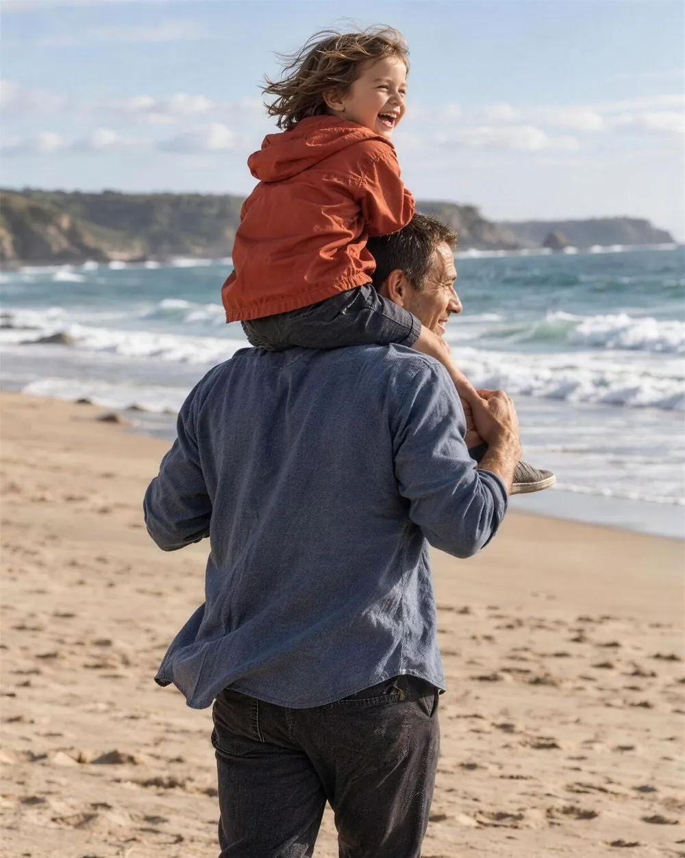 A father carrying his child on his shoulders at the beach